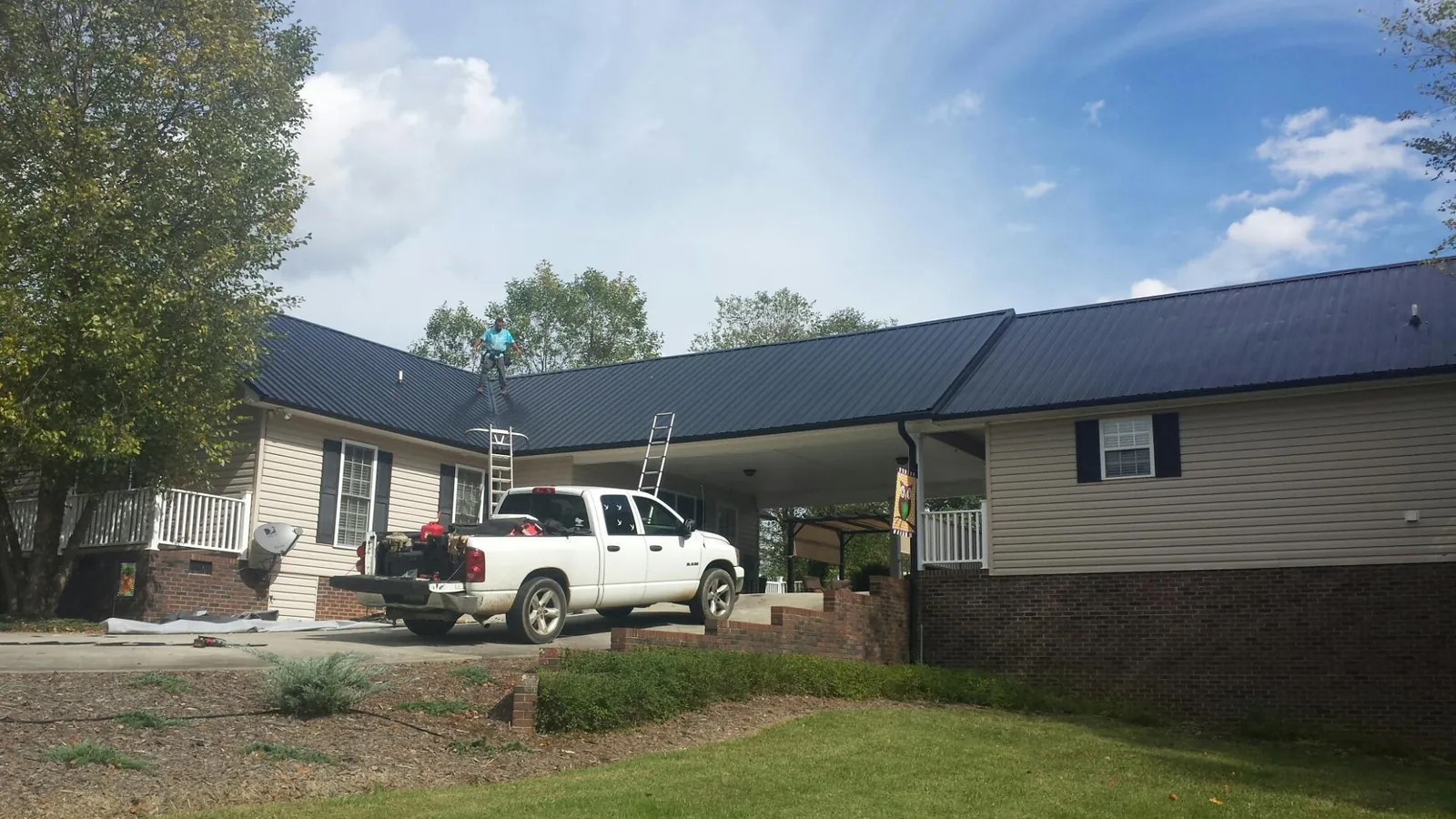 Black metal roof over a home and attached breezeway with ladders set in Lindsay